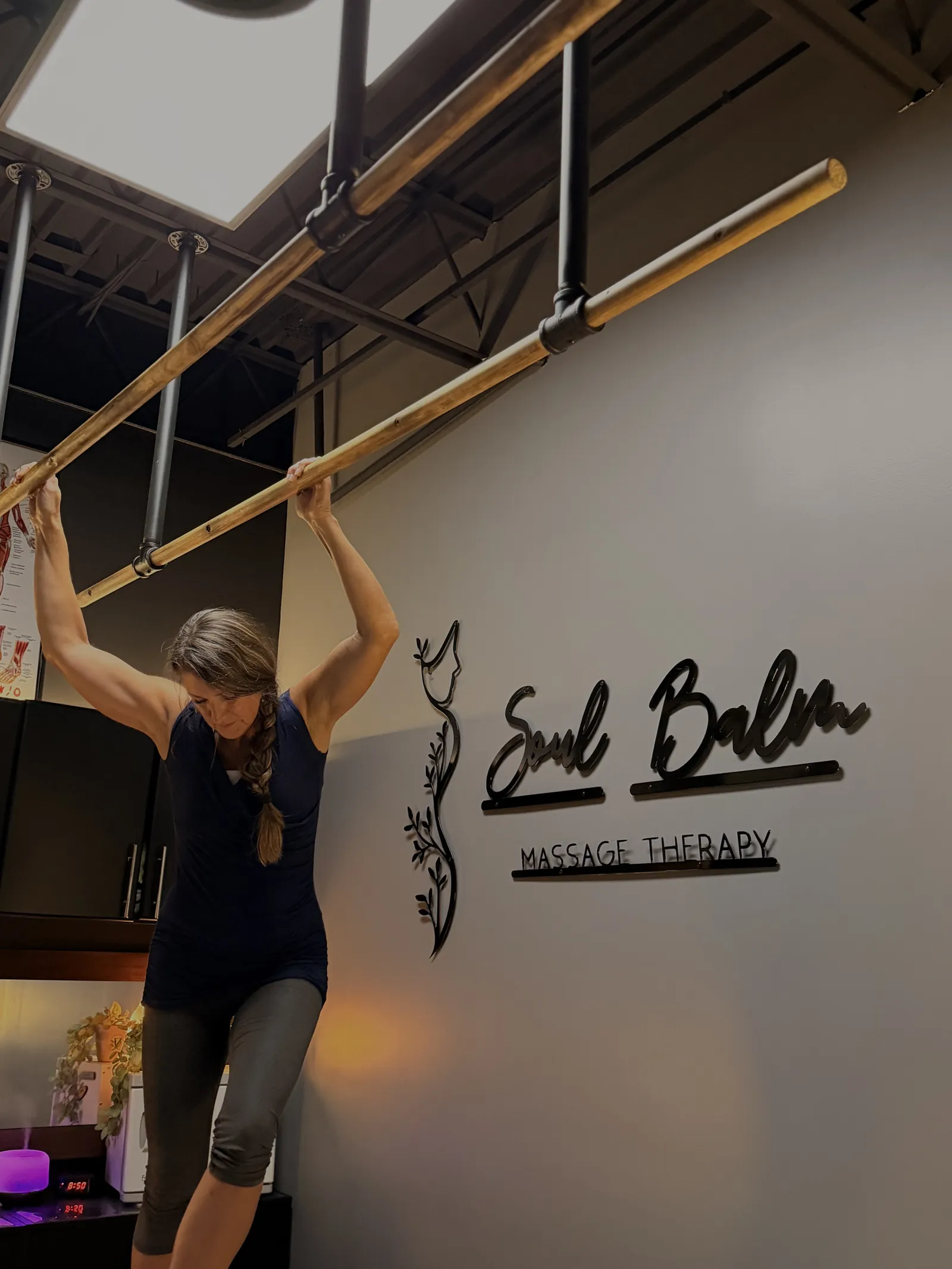 Teresa holding the Ashiatsu support bars beside the Soul Balm sign